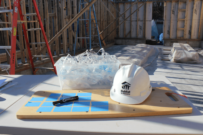 A hard hat and a bin of safety glasses sit on a table, ready for the day's work
