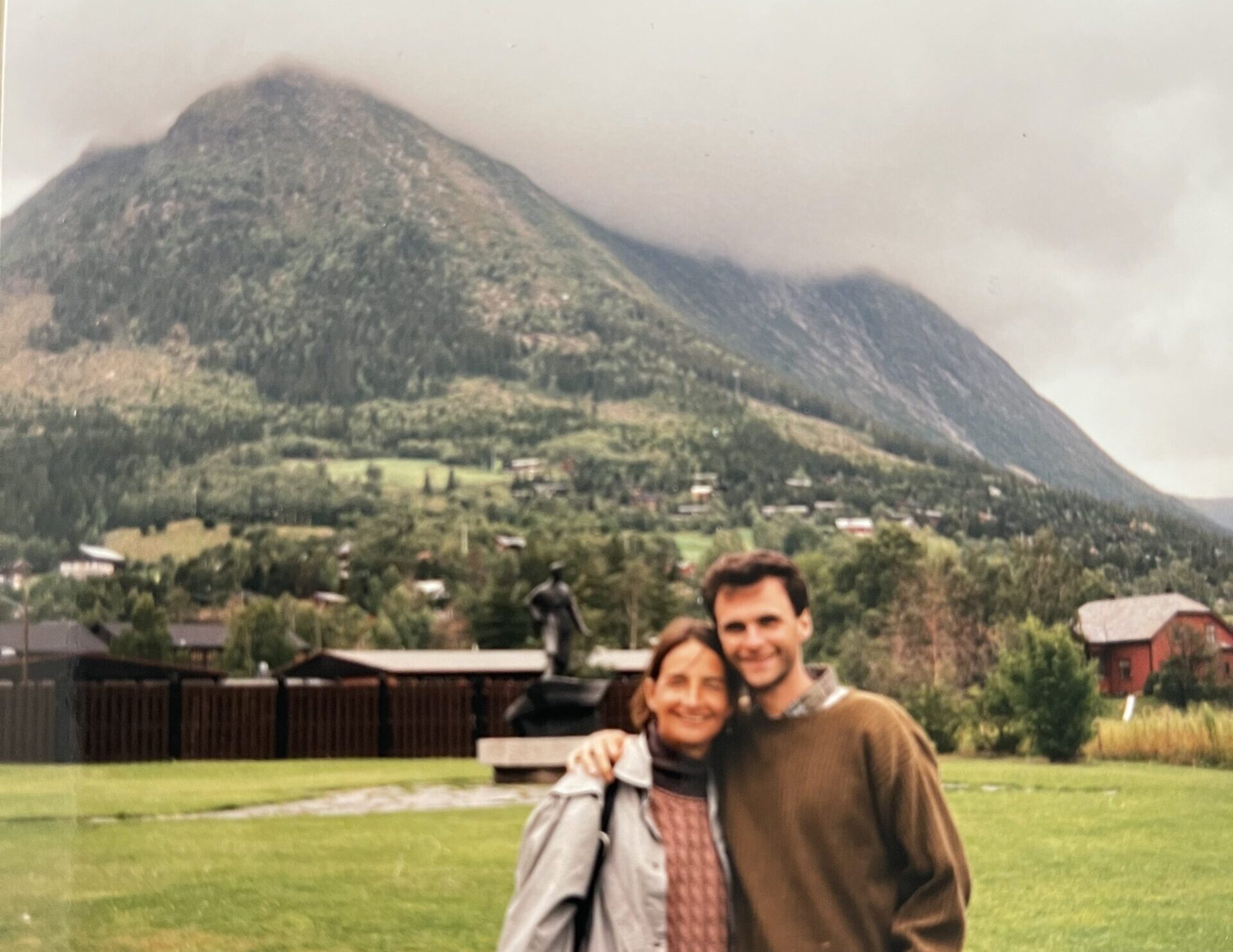 A photo of Ingrid and Doug hugging and smiling in front of a foggy mountain