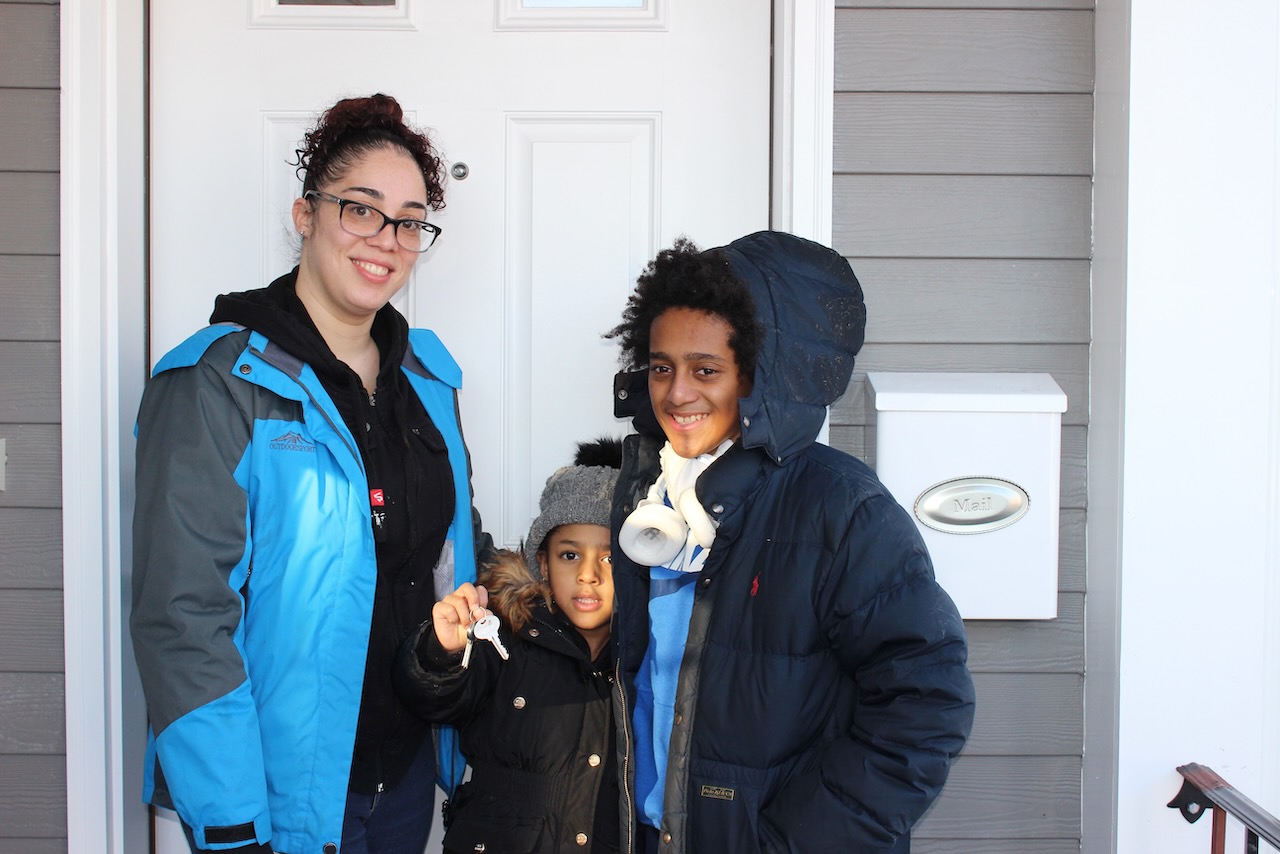 Cynthia and her two children at the front door of their new home