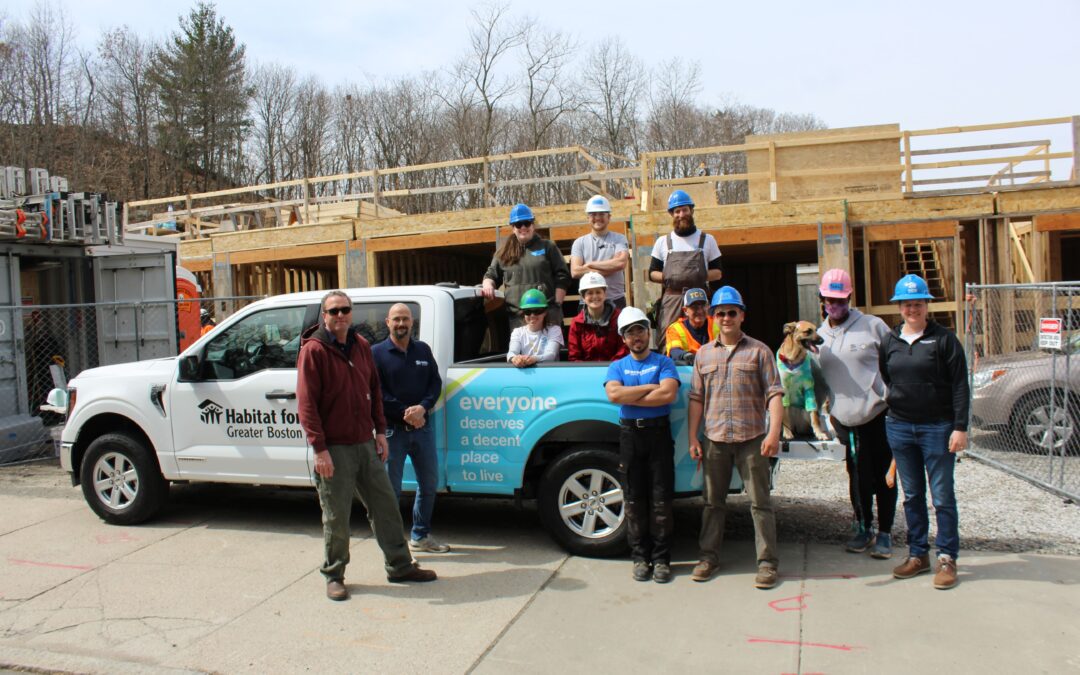 The Habitat Greater Boston construction team poses with a pickup truck with the organization's logo